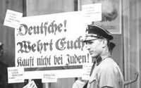 חברי אס אה נאצים תולים כרזה על חלון בית עסק בבעלות יהודים, ובה כתוב: "גרמני, הגן על עצמך. אל תקנה מיהודים".